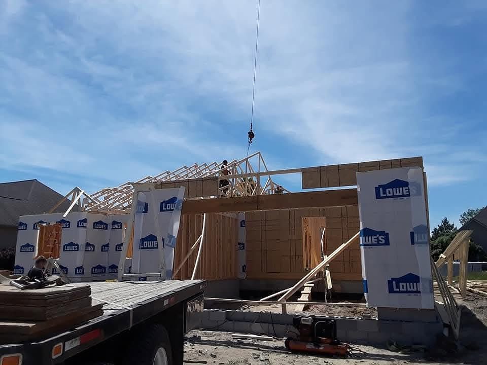 Crane lifting a roof truss onto a new home frame