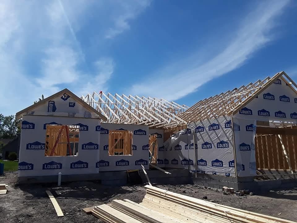 New home under construction with roof trusses and house wrap