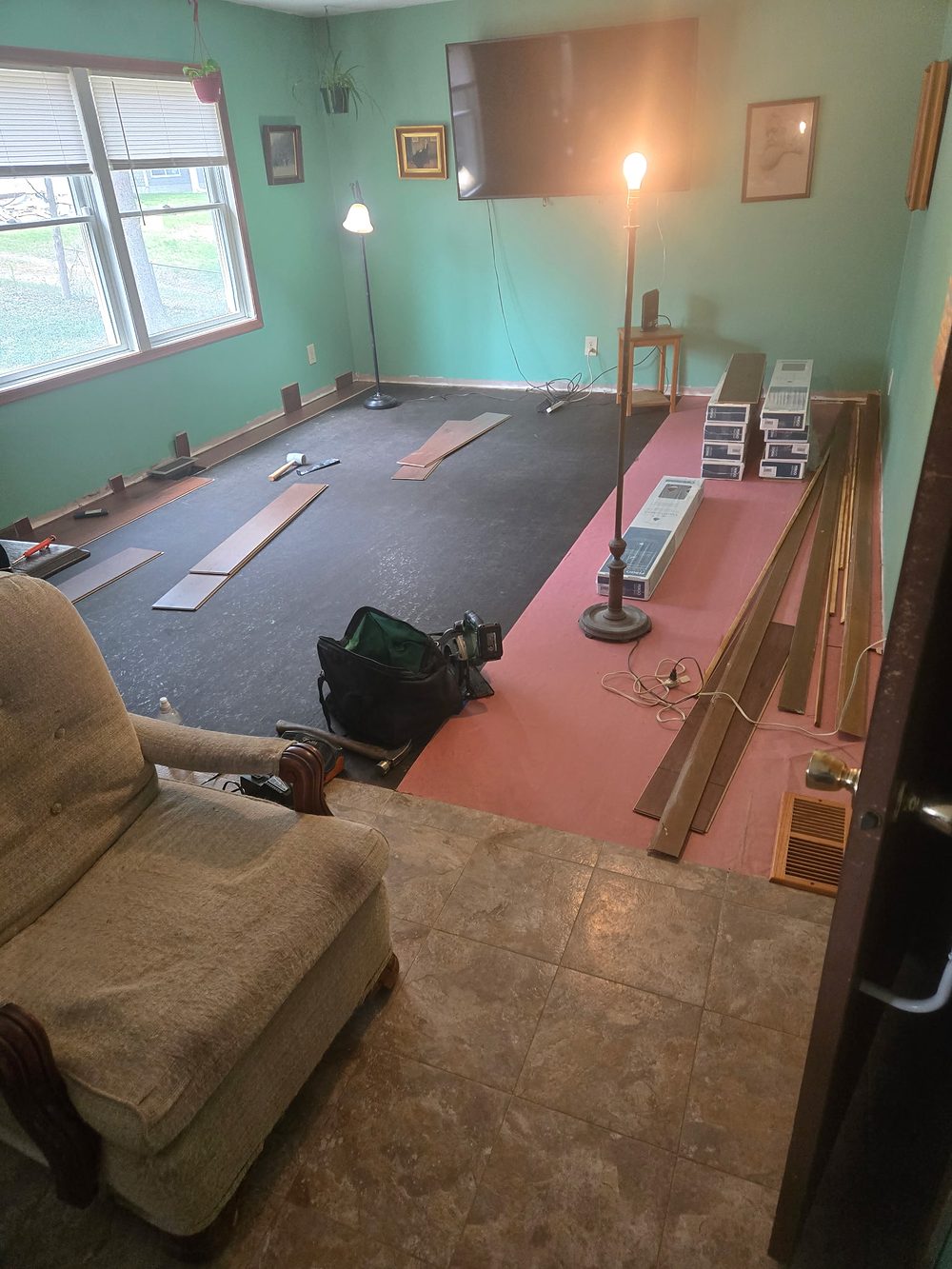 Floor installation in progress, underlayment and planks visible