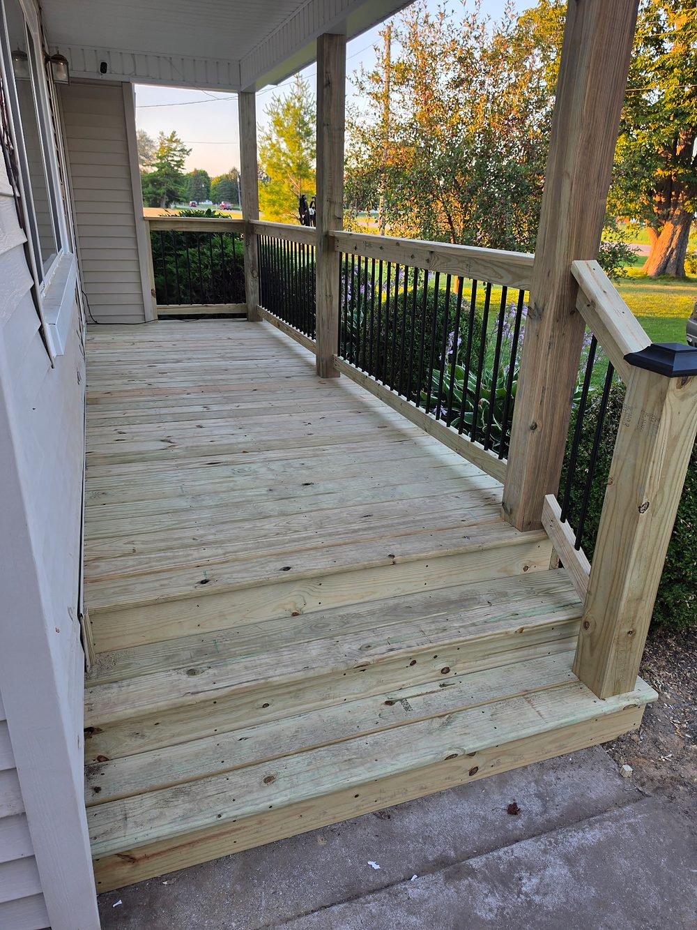 New porch stairs and railing with black aluminum balusters, looking toward the yard