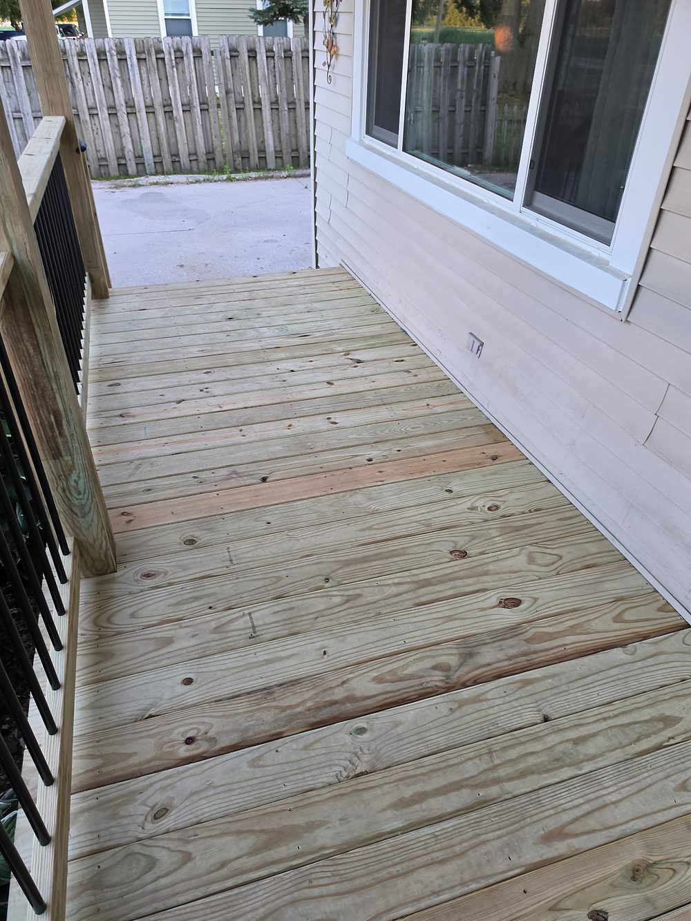 New pressure-treated deck boards running along the front of the house